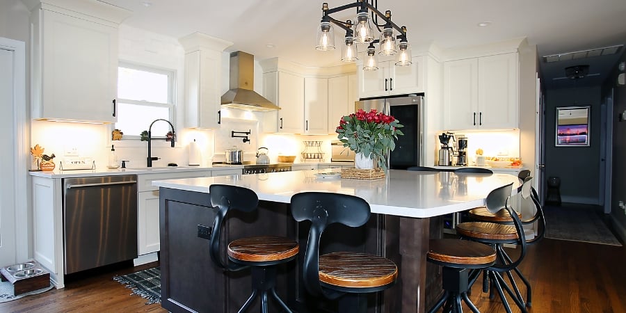 Kitchen island with light above and black barstools in Islip, NY by Kuhn Construction